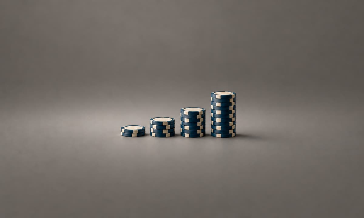 Four ascending stacks of blue and ivory poker chips on a warm grey background